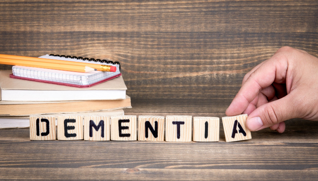 A hand placing wooden tiles with letter on to make the word dementia