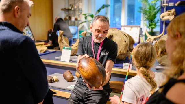 A museum employee shows a wooden artifact to a group of people at the World Museum in Liverpool.