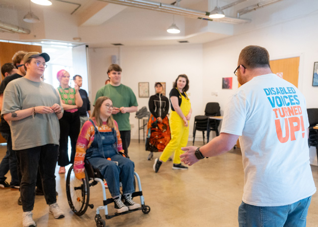 A Drama instructor standing in front of a group of people at The Brain Charity