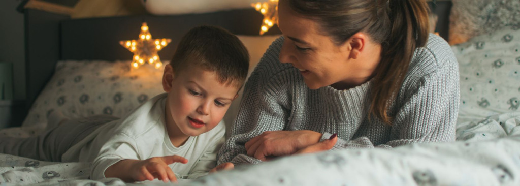 A boy playing on a bed with his mother
