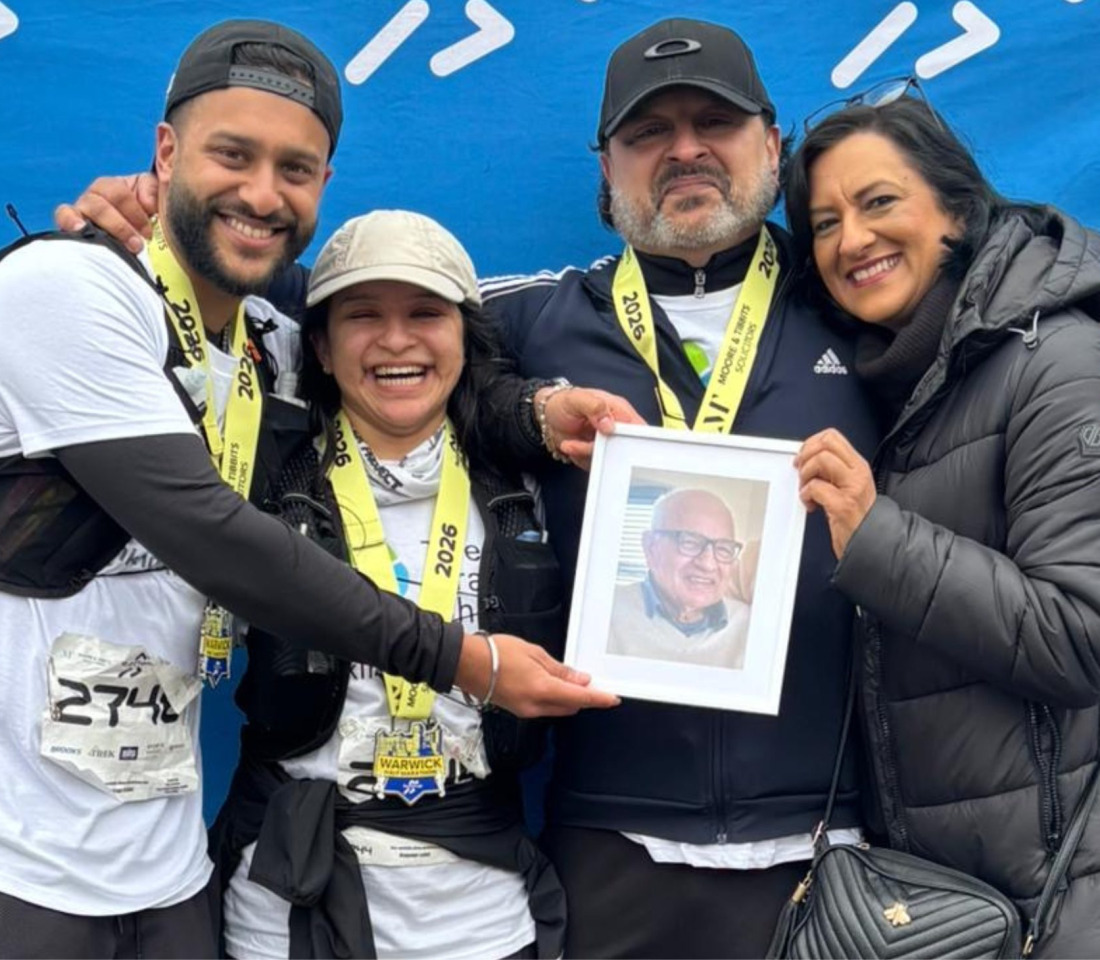 The Bains family posing with a photo of their grandfather.