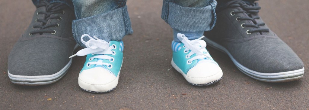Feet of a child beside feet of a man