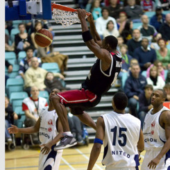 A basketball game with a player grabbing the hoop and scoring