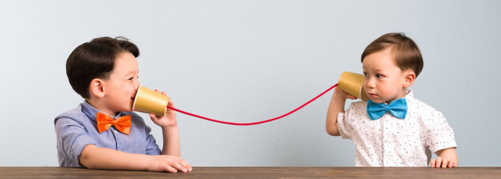 Young boys using cups and string as a telephone