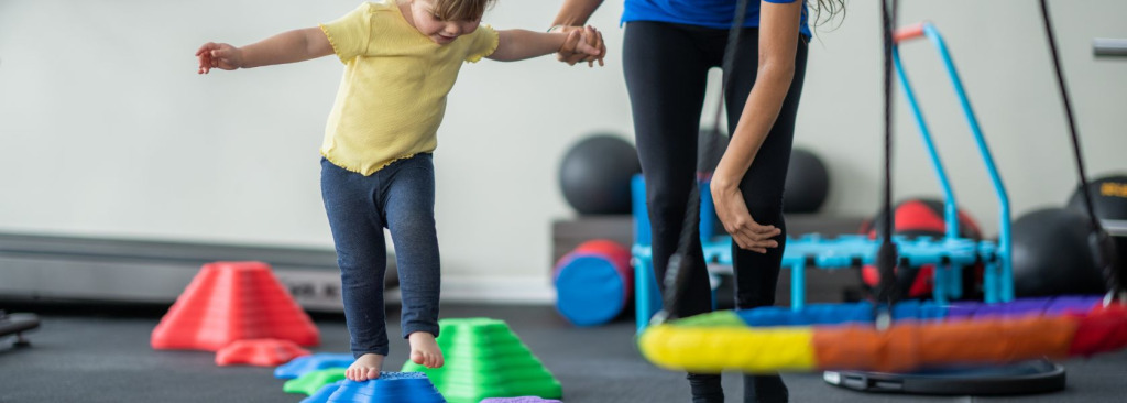 young girl walking over a colourful obstacle course of different sized steps