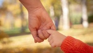 An adult holding a child's hand