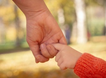 An adult holding a child's hand