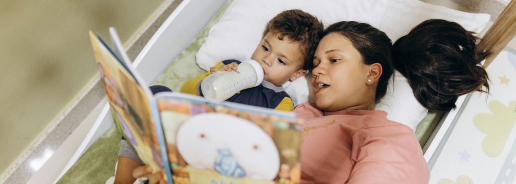 A mother reading a book to a child in bed