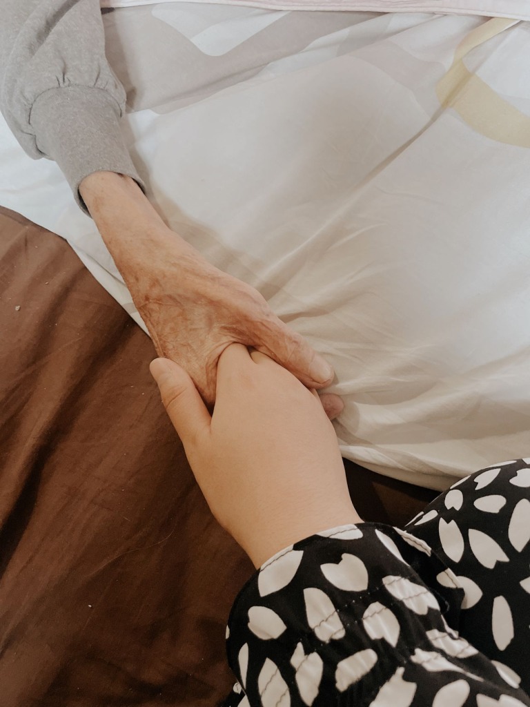 An older and a younger person holding hands.