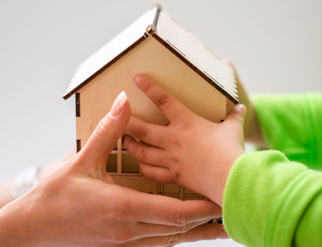 Adult and child holding wooden house